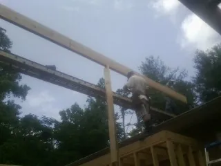 Carpenter setting a ridge beam over a new addition frame — Ice Dam Removal by Roofing Brothers in Ponca