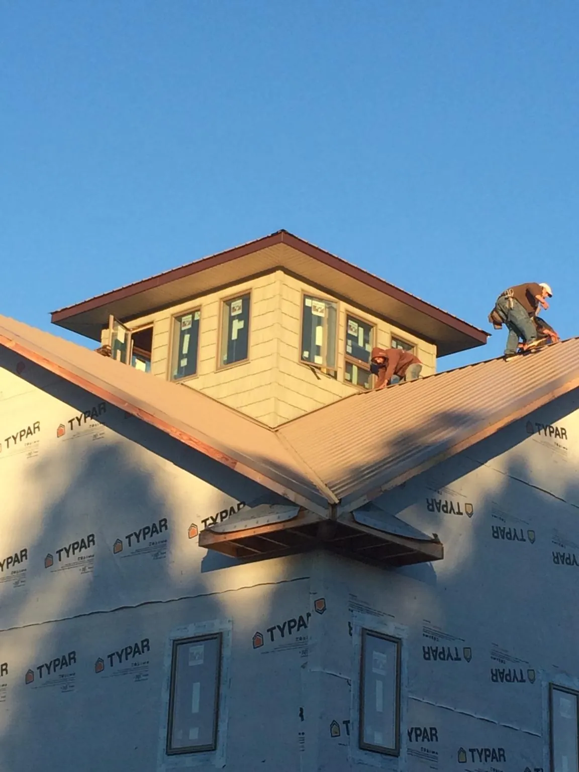 Roofers working around a rooftop cupola on a new metal roof at sunset — Roof Waterproofing in Ponca by Roofing Brothers